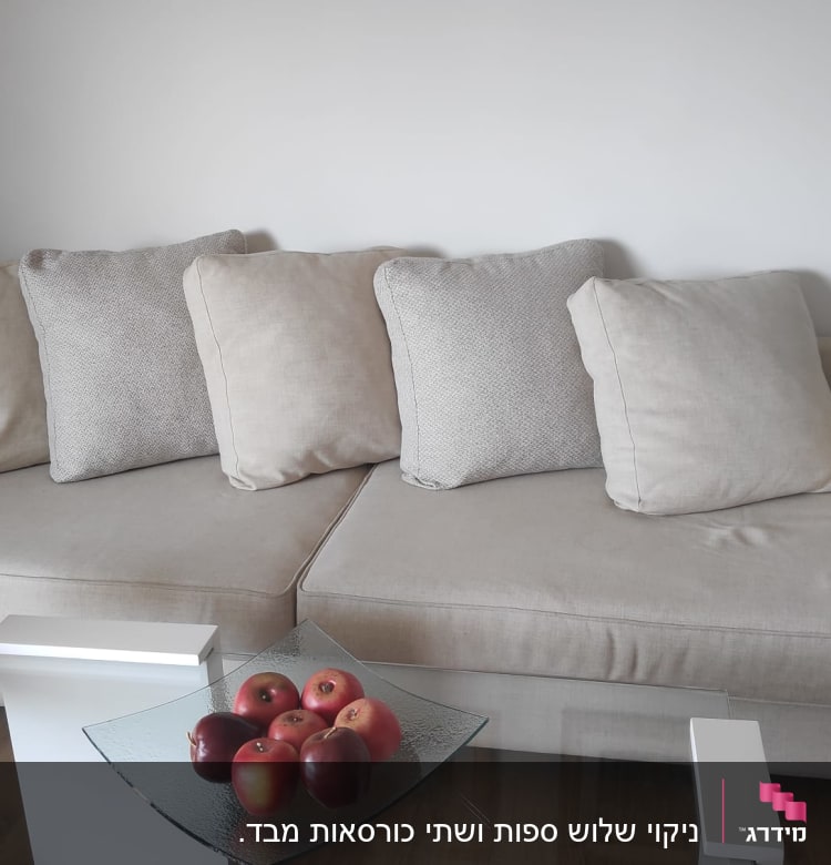 ספה בהירה עם כריות על רקע קיר לבן